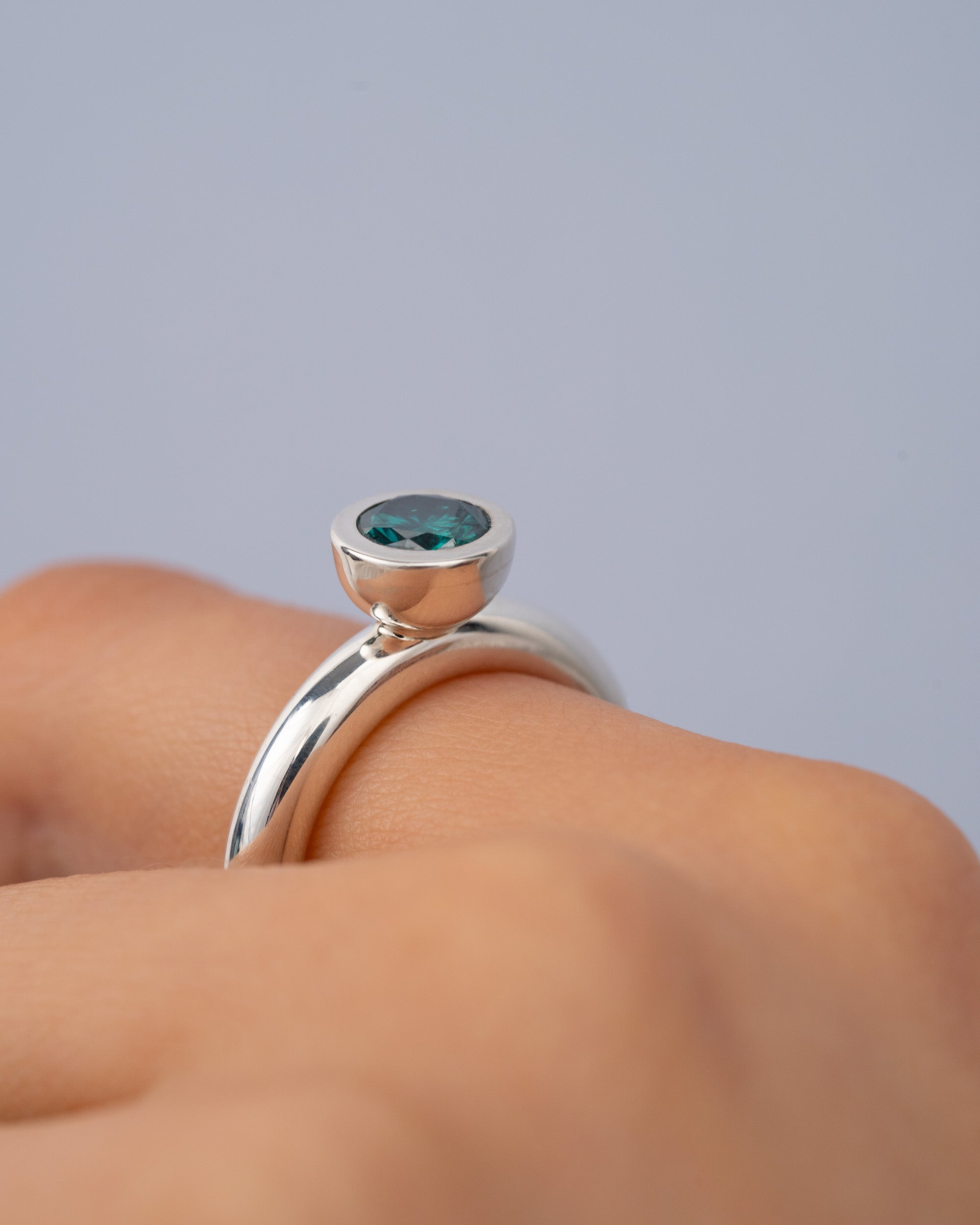 Silver close up shot of ring with Green moissonite center stone on hand